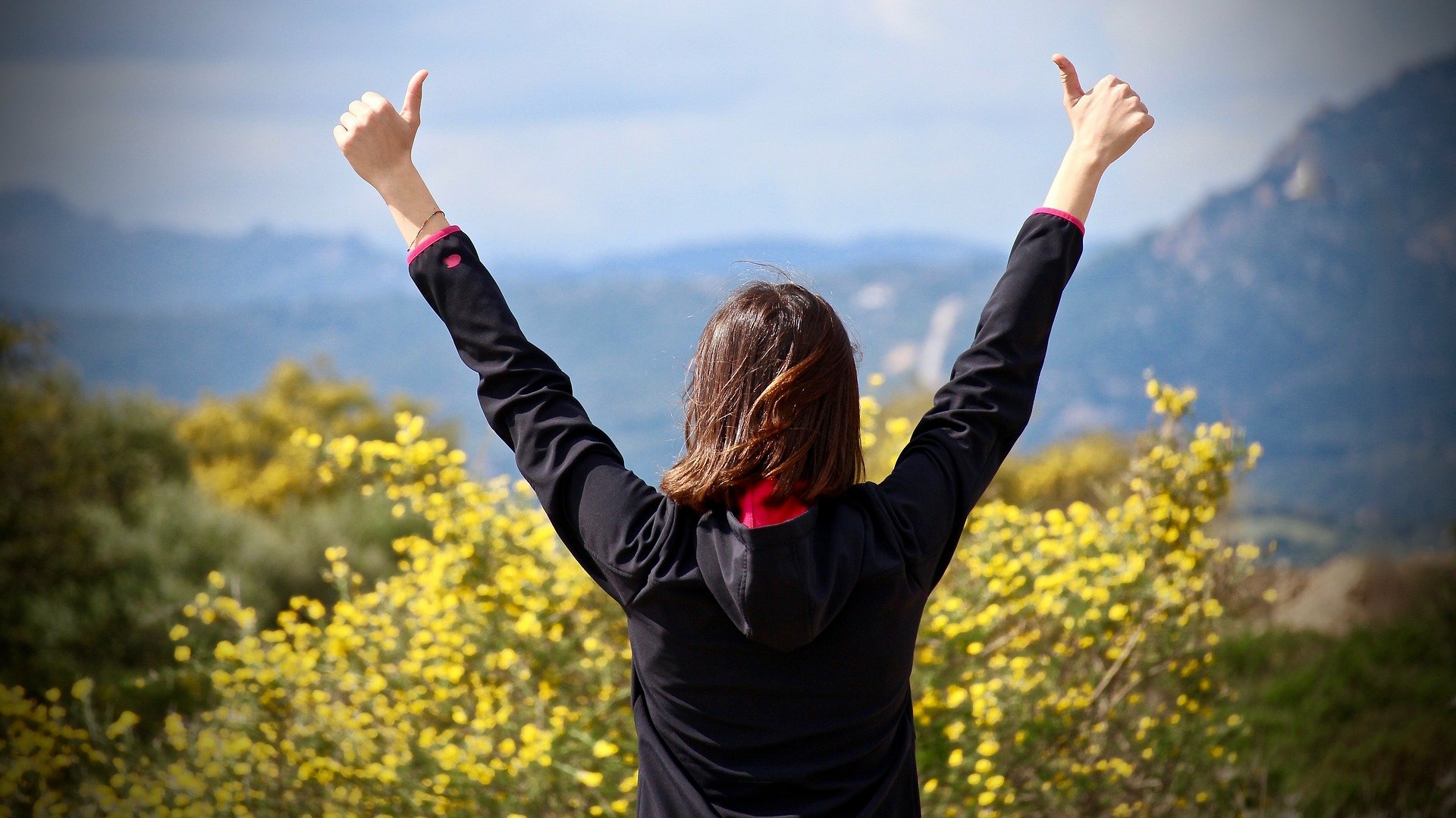 woman standing in nature with hands up in the air