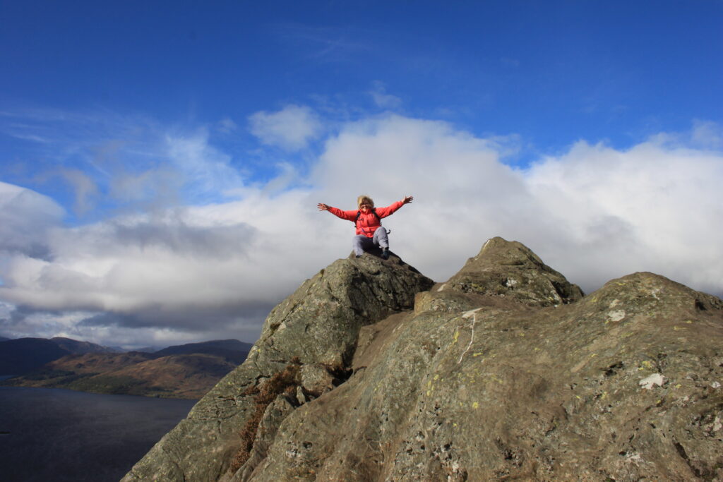 person with arms extended sitting on mountain top