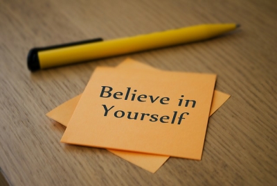 pen and paper with believe in yourself written on it