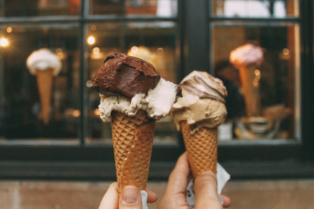 two hands holding chocolate ice cream cones