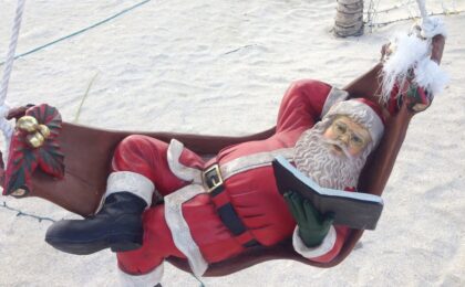 Santa swinging in a hammock reading my 12 alternative buzzwords of christmas book