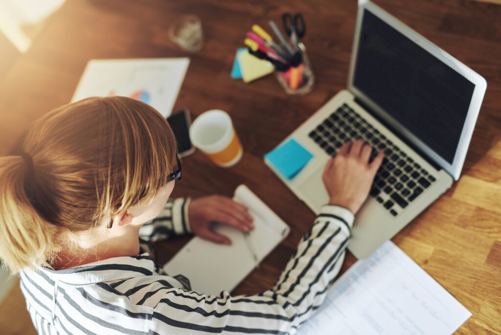 woman reading 25 blog post ideas and using those ideas to write her own blog on her laptop