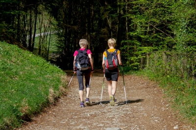 two women walking in nature wearing backpacks