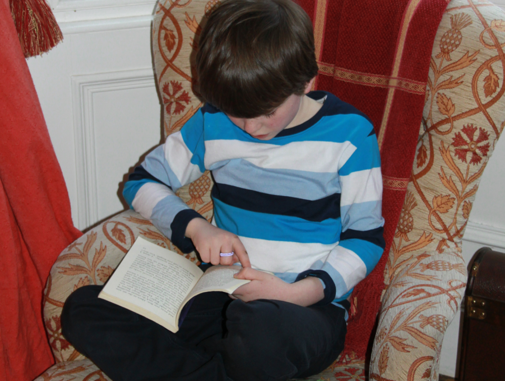 boy sitting on a chair reading a book