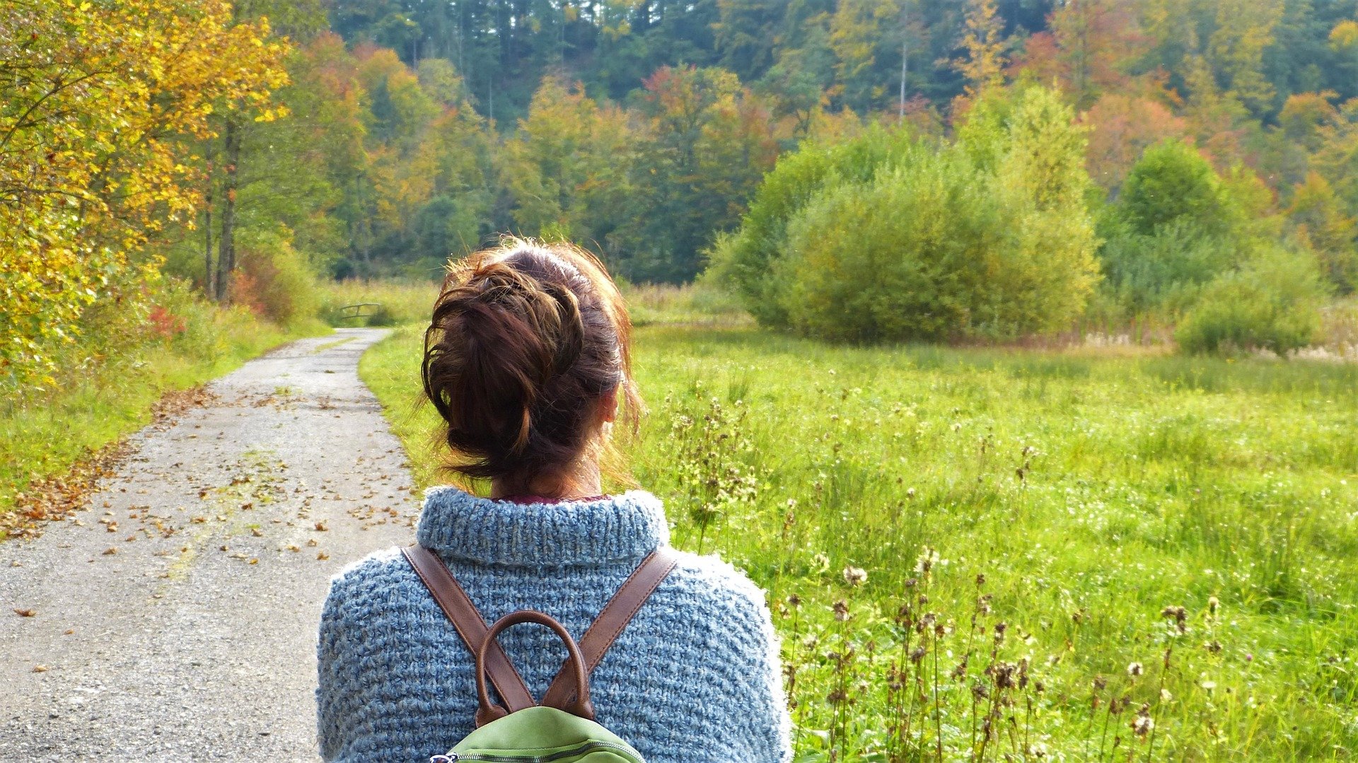 woman walking in nature wearing a backpack