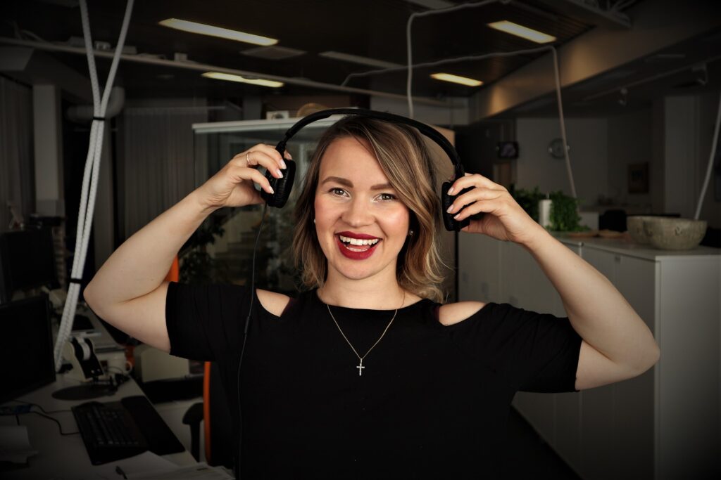 smiling woman in black top taking headphones off after giving advice in a podcast