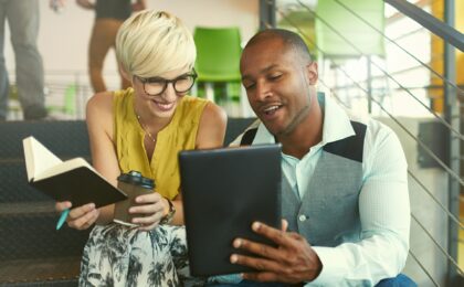 couple sitting on stairs looking at mobile device finding out how to make money selling information products
