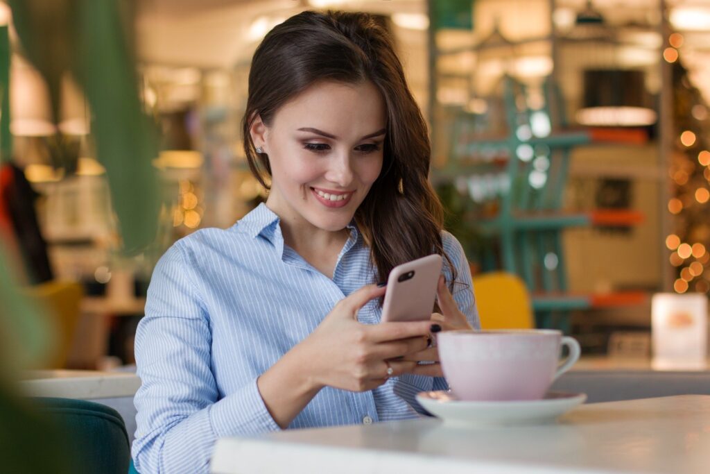 smiling woman in cafe reading 12 quick free traffic hacks guid on her smartphone