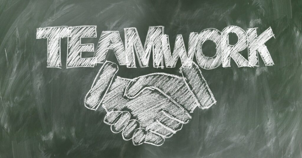 shaking hands drawn on a blackboard with teamwork written above them