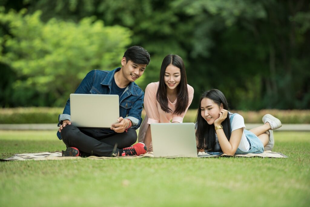 3 people reading tips for creating compelling content on their laptops in a park