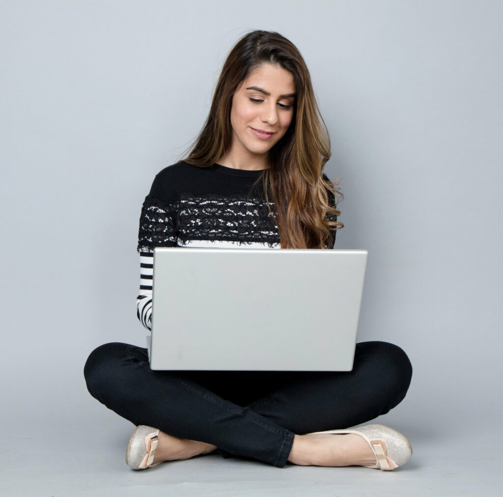 woman sitting with legs crossed setting up and making money with fiverr on her laptop