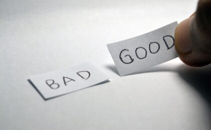 the words good and bad written on post it notes with a hand holding the good one