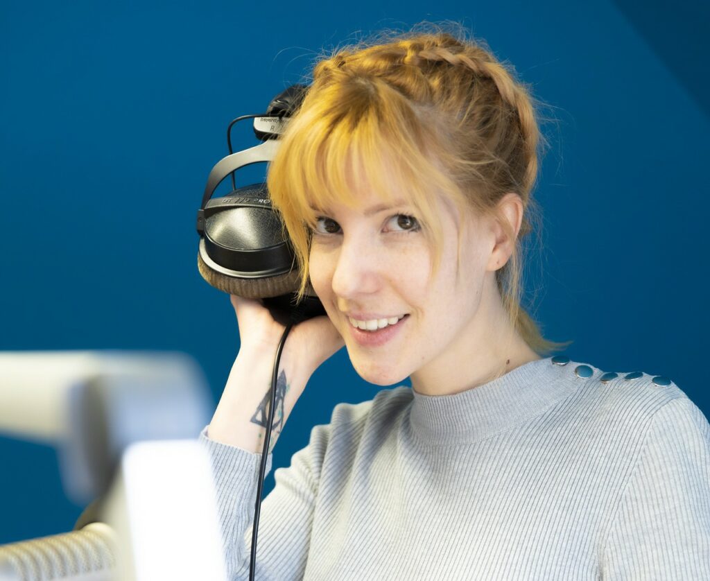 woman holding headphones listening to a podcast