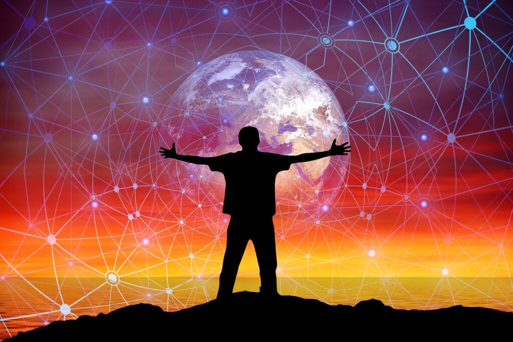silhouette of man standing on a rock looking out to a rainbow coloured sky and ocean holding a globe with lots of social media networks coming surrounding it