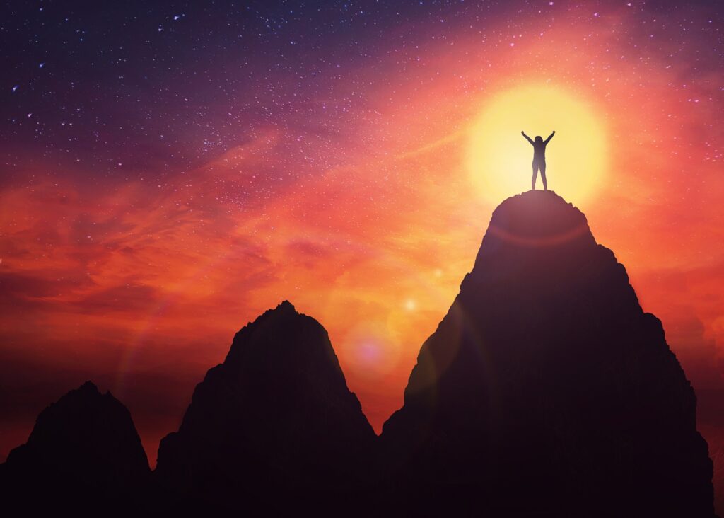 a silhouette figure with arms outstretched standing at sunset on top of the highest of three mountains after having successfully applied 5 ways to increase your business profits blog ideas