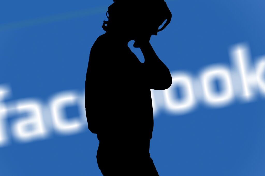 silhouette of frustrated woman in front of facebook banner wishing she'd read how to avoid losing money with facebook ads blog