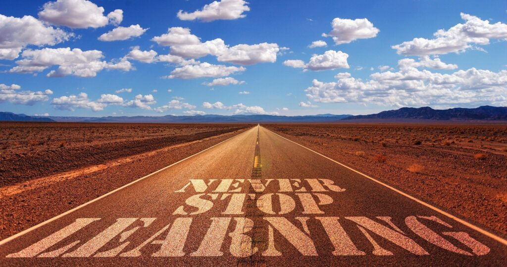 the open road with blue sky and clouds with the words never stop learning written on it