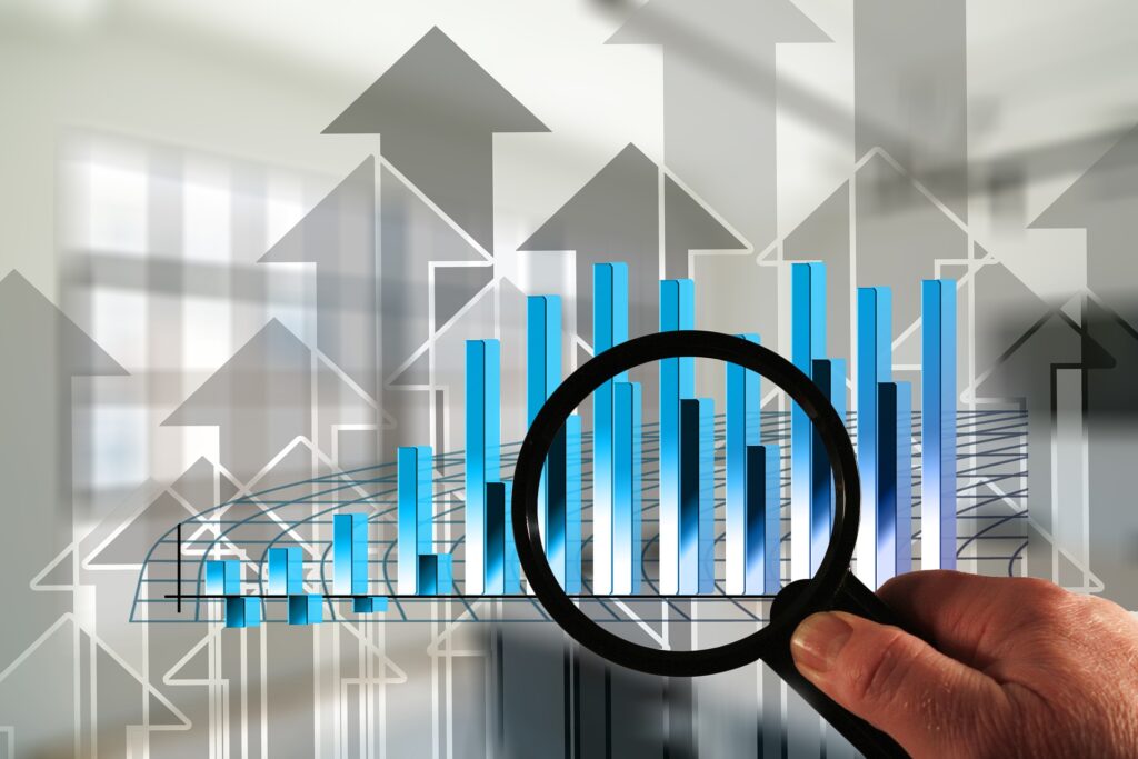 hand of someone who has applied tips to help their business grow holding a magnifying glass focused on a bar chart with upwards arrows in the background