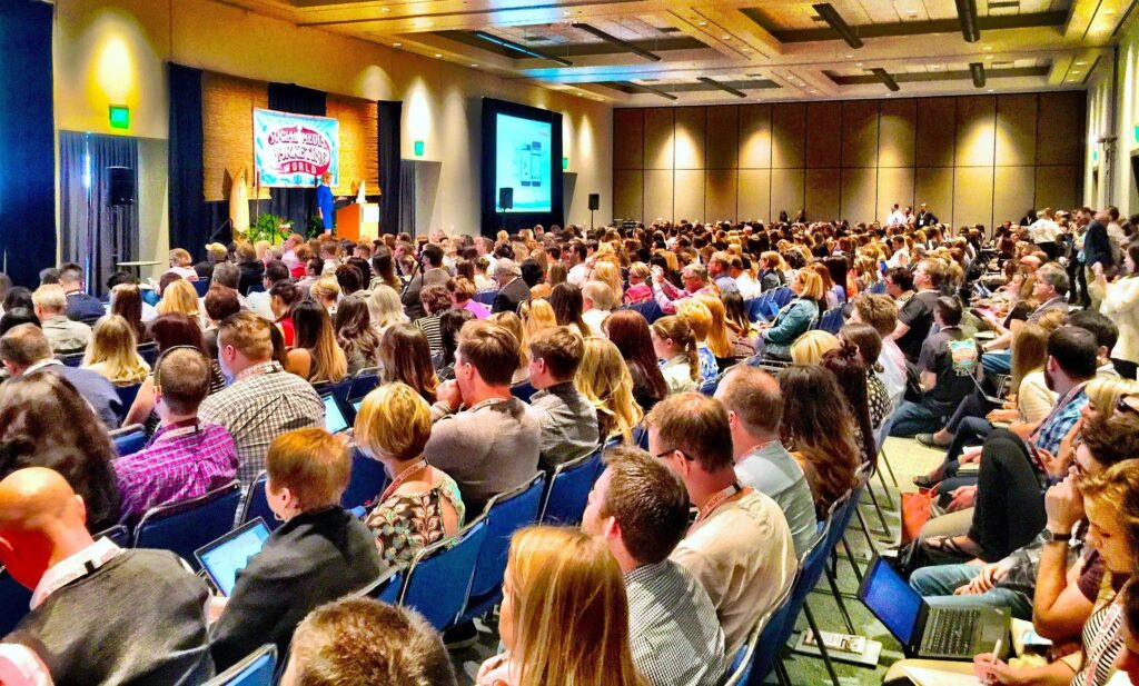room full of people at a seminar learning from a speaker the 5 reasons why some businesses fail