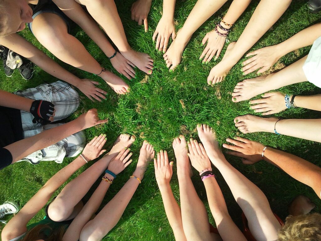 community of people in a circle showing their hands and feet