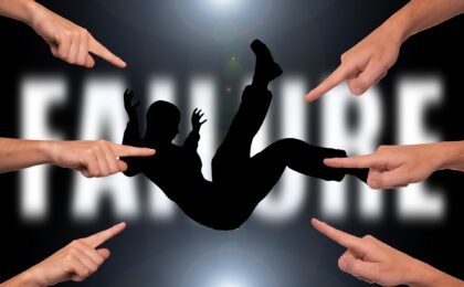 silhouette of a person floating in front of the word failure with a group of people pointing fingers at them. Featured image of 5 reasons why some businesses fail blog post.