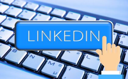 finger pressing linkedin button with keyboard in background